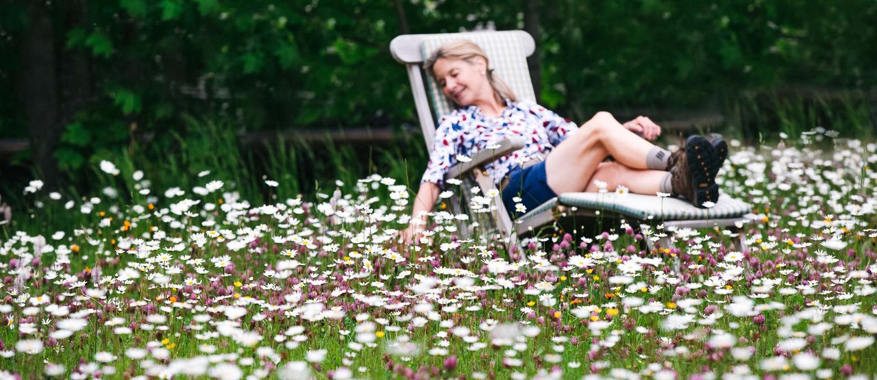 Aurora Garten Dame liegt am Liegestuhl in einer Blumenwiese