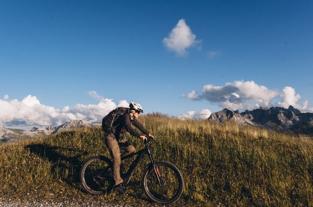 Radfahren in Lech Mountainbikerin fährt über die Almwiesen.