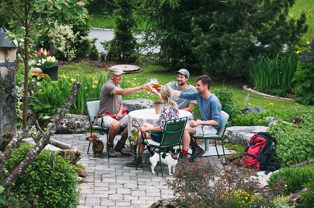 Personen an einem Gartentisch prosten sich zu