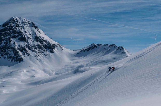Skiabfahrt im Pulverschnee Eine Person fährt mit Ski den verschneiten Hang hinunter