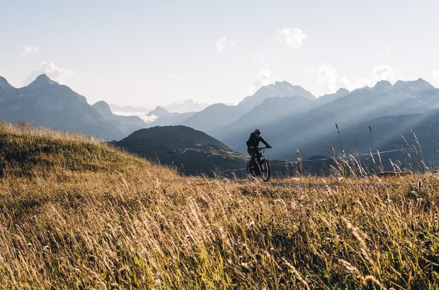 Biken in Lech Bikerin auf dem Fahrradweg mit traumhaftem Bergpanorama.