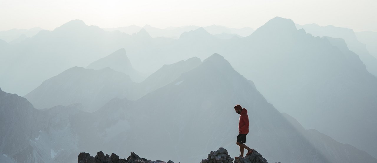 Sommerurlaub in Lech Mann wandert über schroffes Gestein vor einem atemberaubendem Bergpanorama.