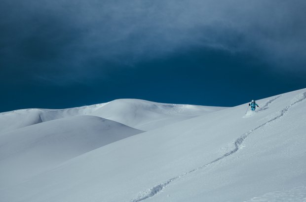 Skifahren in Lech Blauer Himmel, schneebedeckte Landschaft und ein Skifahrer am wedeln.